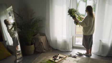 woman holds festive wreath for christmas looking in mirror