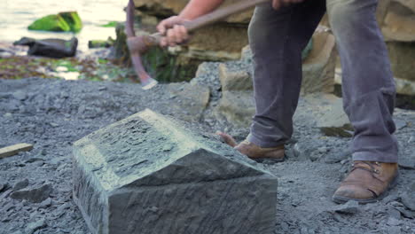 handheld medium wide shot showing a stone craftsman carefully chipping at a block of stone to shape it, in the city of ancud, chiloe island