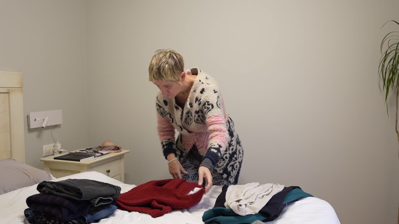 Woman folding clothes in bedroom