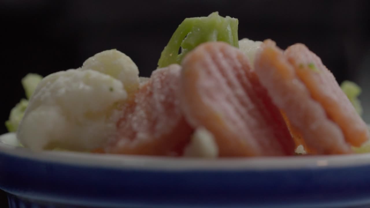 A plate rotates showing cooked vegetables with soft textures under warm indoor lighting