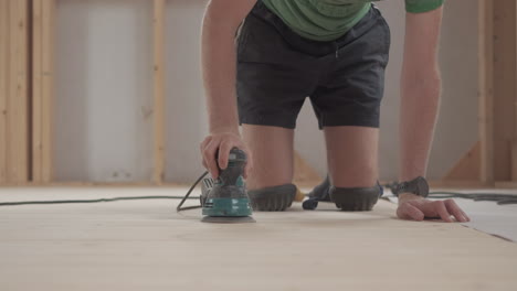 man sanding down a wooden floor