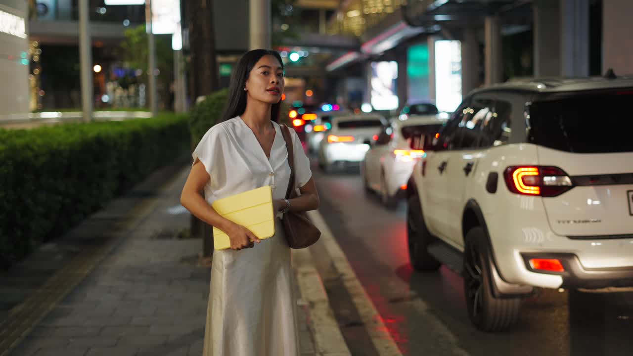 Woman waiting for a taxi at night in the city