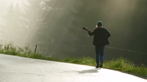 Un-Músico-Camina-Al-Lado-De-Una-Carretera-Tocando-La-Guitarra