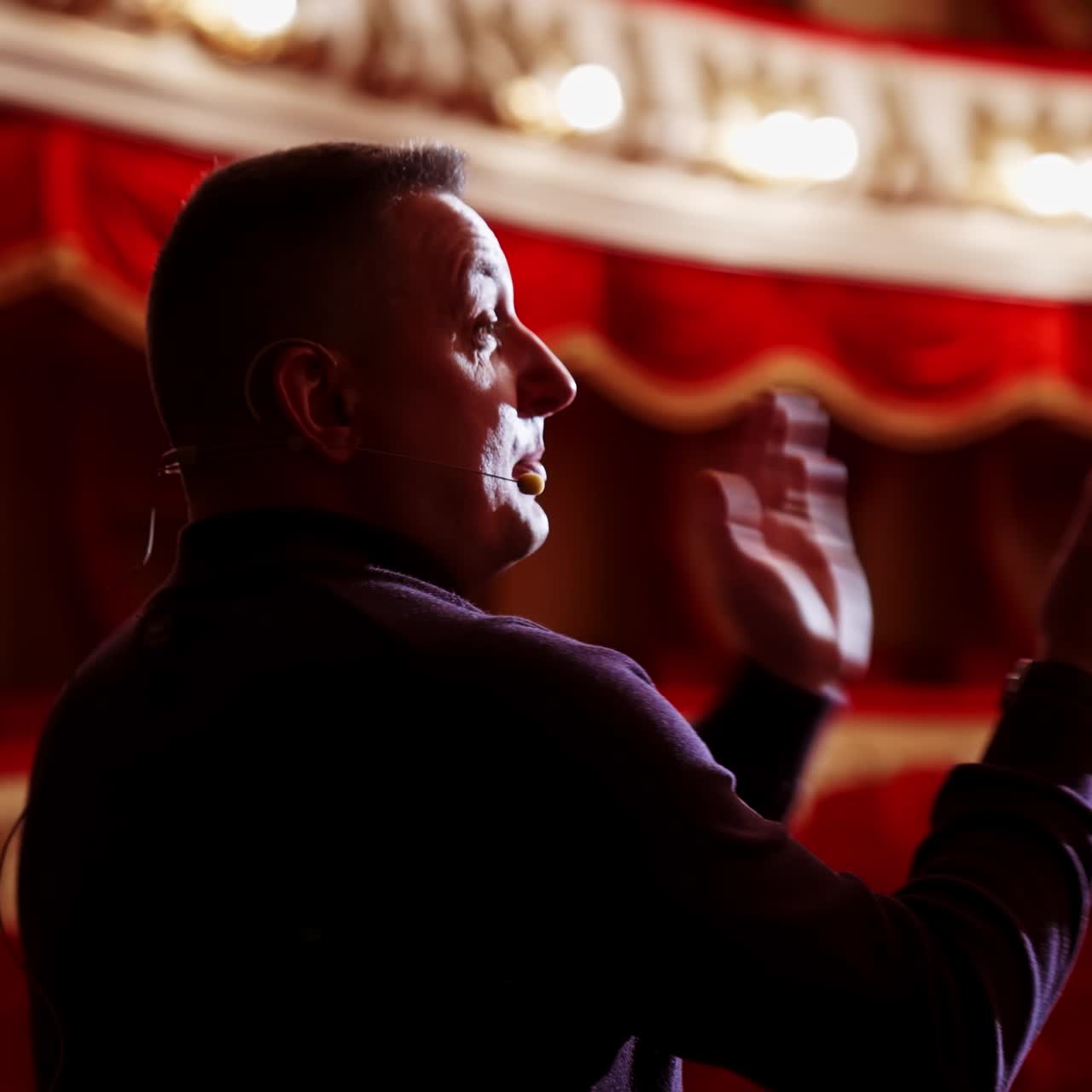 Man entertainer, presenter or actor on stage. Active gestures of clapping to the auditorium. View of a male public speaker speaking at the microphone