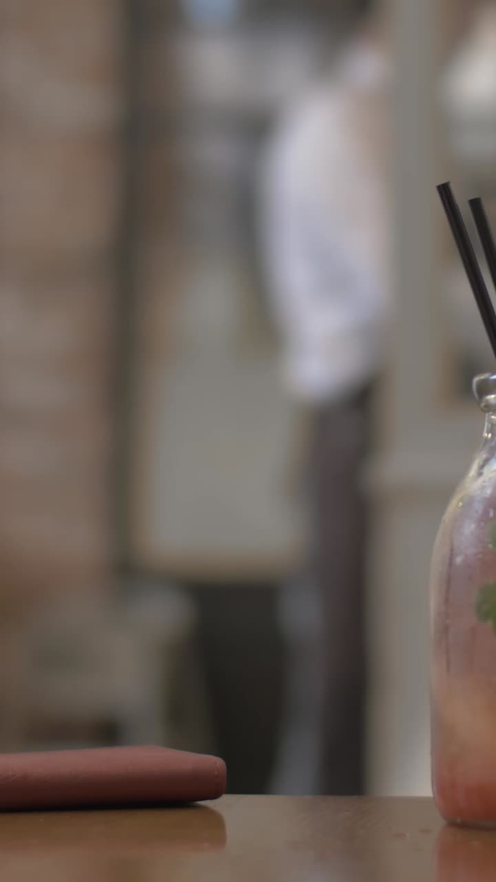 Main posant une boisson rafraîchissante à la menthe et aux agrumes sur une table