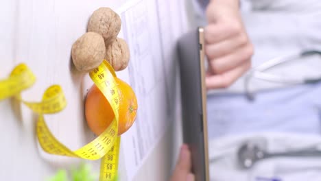 vertical video, diet specialist using a table during a dieting appointment, walnuts and tangerine on desk