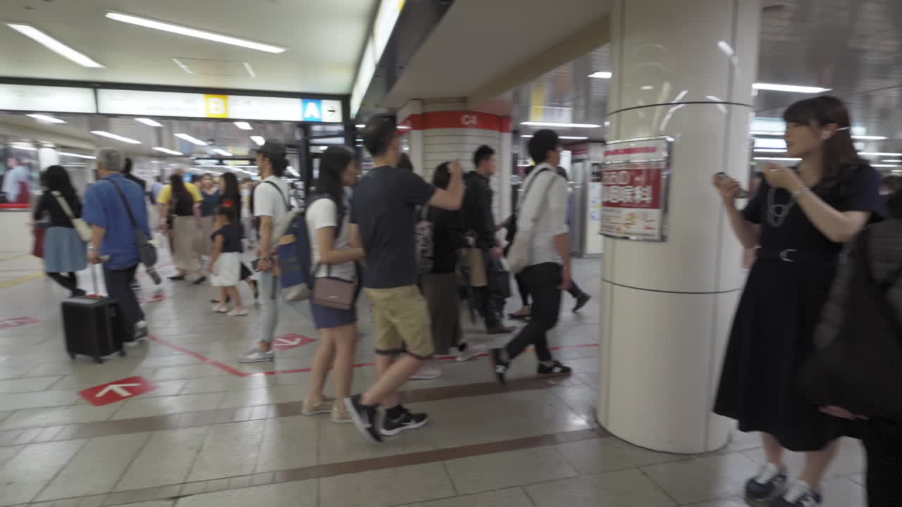A busy section of Namba Walk in Osaka, Japan, full of pedestrians heading to their destinations, medium spin in slow motion.