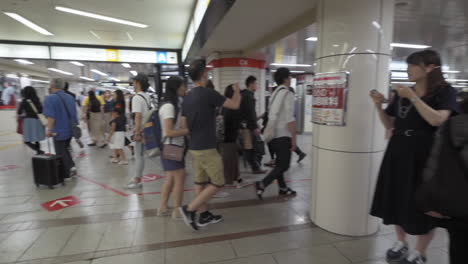 a busy section of namba walk in osaka, japan, full of pedestrians heading to their destinations, medium spin in slow motion.