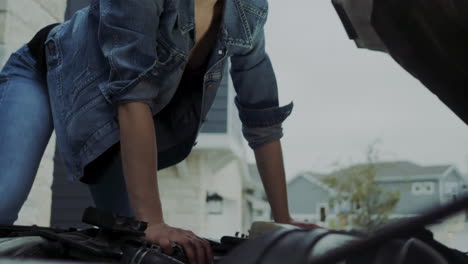 Woman-in-early-20s-checking-under-the-hood-of-a-truck-and-going-under-the-truck-to-find-and-fix-mechanical-problem