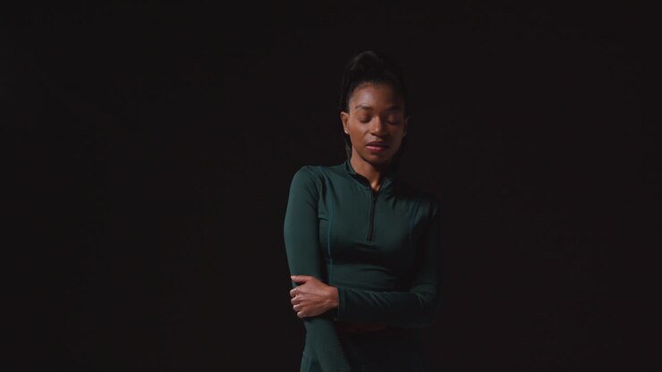 Portrait Of Determined Female Athlete Wearing Tracksuit Training Warming Up And Stretching Against Black Studio Background 1