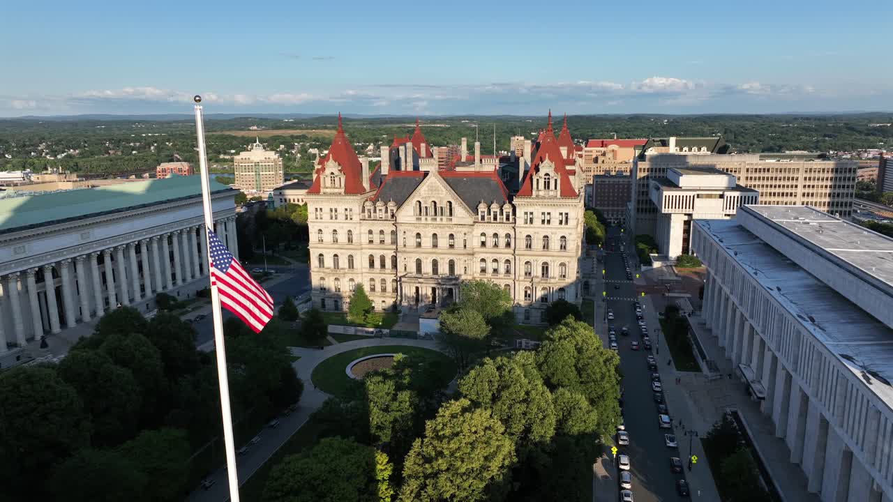 Patriotic American flag at half-mast in Albany city. Sunset time in American town. Neat park area of New York State capitol and chancellor hall. New York, USA. Peaceful film scene