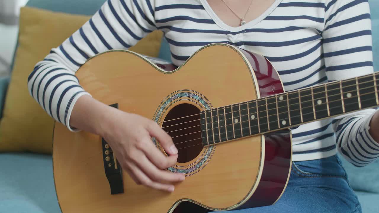 cerca de las manos de la mujer tocando la guitarra en casa
