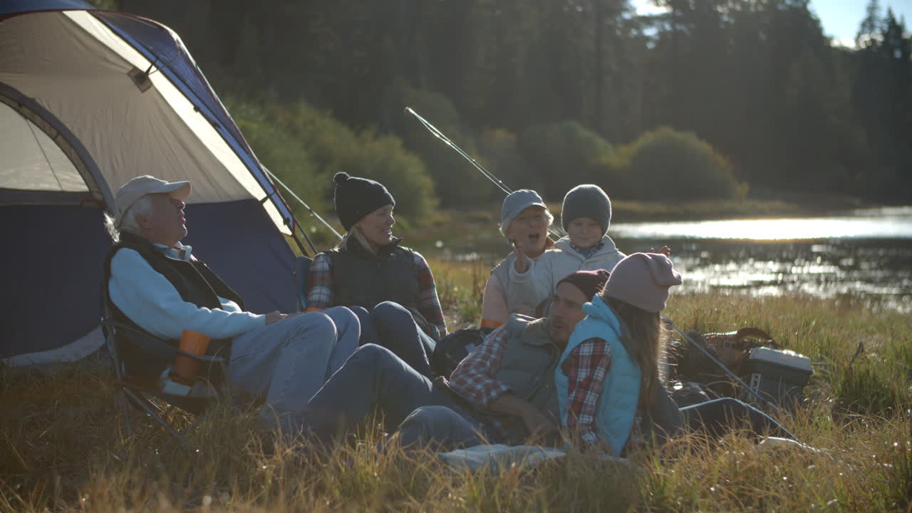 여러 세대의 가족이 시골에서 텐트 밖에서 휴식을 취하고 있습니다.