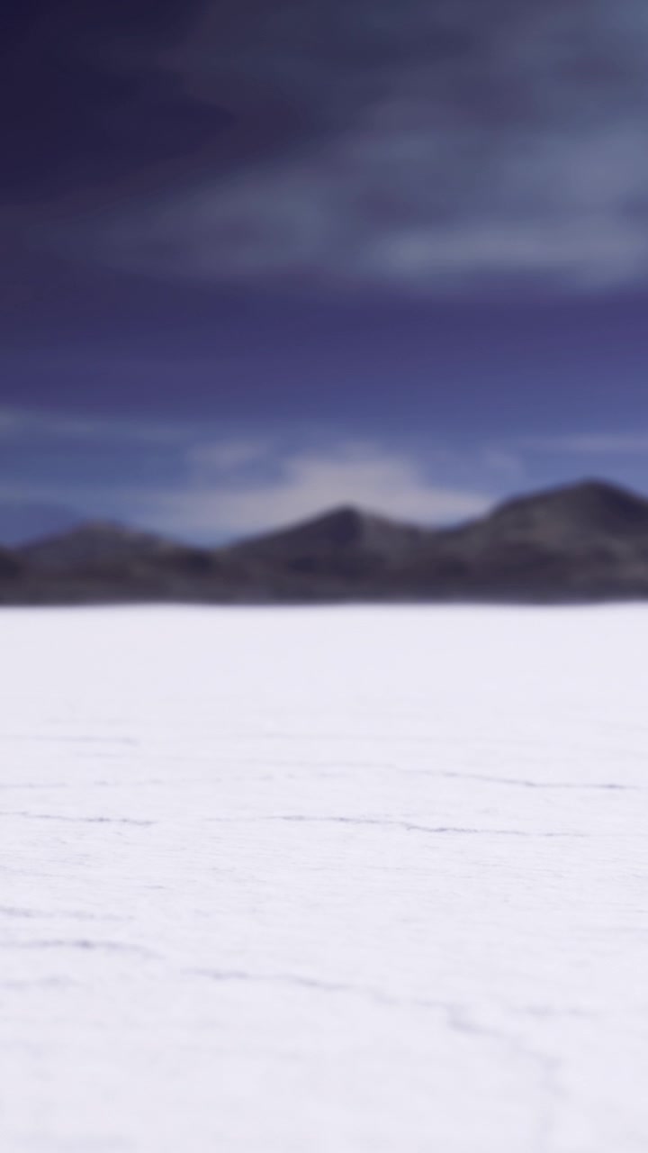 Salt flat landscape with distant mountains under cloudy sky