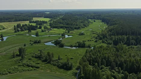 Aerial-of-a-flowing-river,-wheat-field,-and-a-country-road