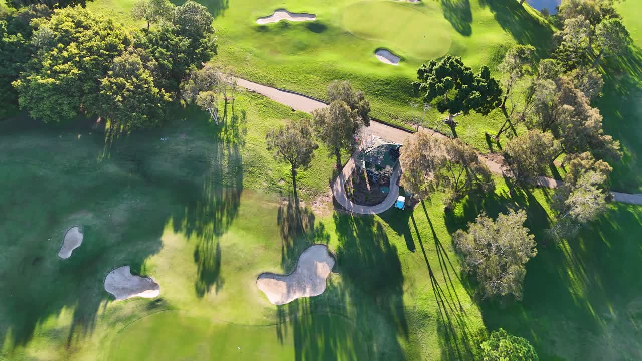 Drone footage captures a lush golf course with sand traps and trees under bright sunlight in Gold Coast, Australia