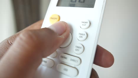 person using air conditioner remote control