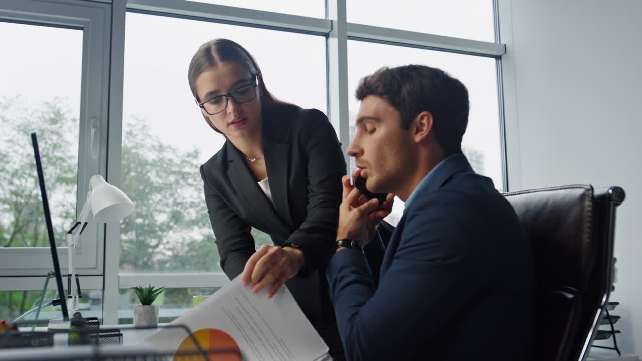 gerente corporativo hablando por teléfono en la oficina. asistente hermosa trayendo contrato