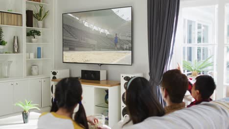 composite of happy family sitting at home together watching athletics long jump event on tv