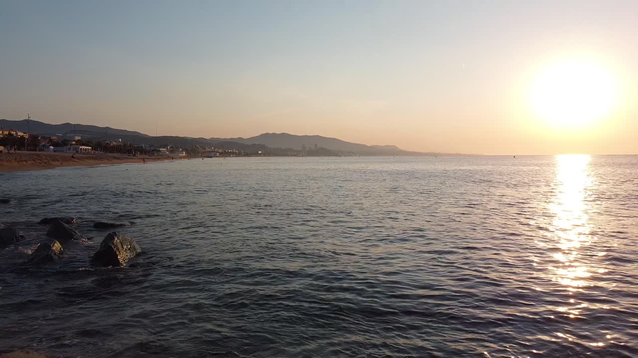 пролетая под причалом на пляже и летя в сторону живописного пейзажа с заходящим солнцем, отражающимся в море