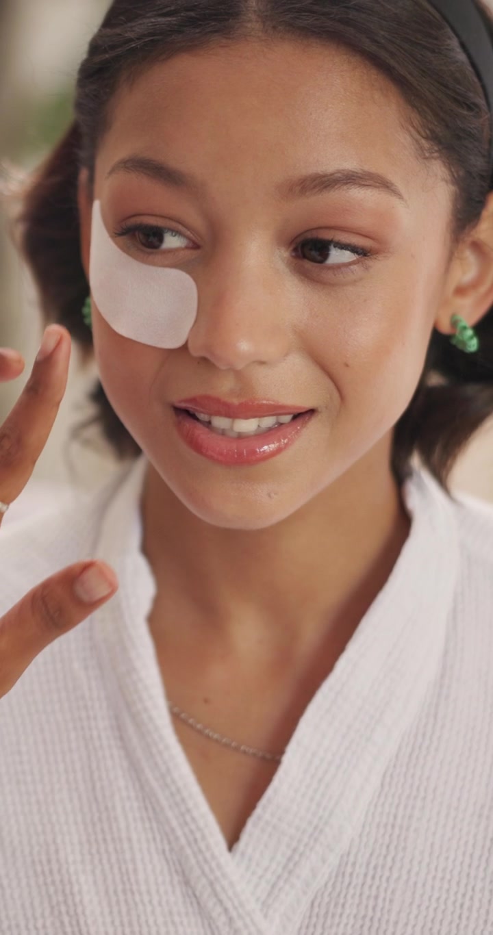 Young Woman Applying Under Eye Patch in Spa Setting