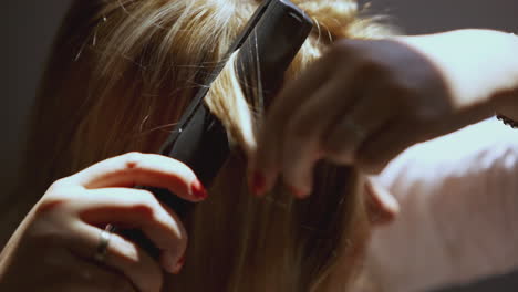 woman straightening her blonde hair