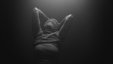 a mummy of a woman on a dark backdrop turns her head
