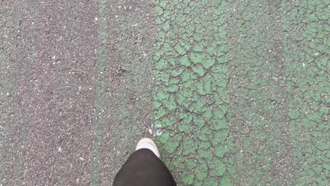 beautiful shot of feet in white sneakers and black pants walking along a destroyed track with traffic signs during the day