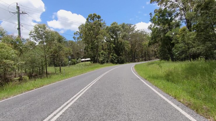 Rear facing driving point of view POV of a deserted Queensland country road with telegraph poles and blude sky - ideal for interior car scene green screen replacement