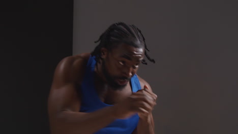 studio shot of male boxer training in gym sparring and sweating warming up preparing for fight 3