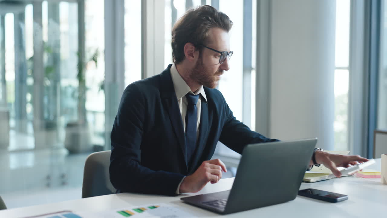Forretningsmand beregner og arbejder på bærbar computer på et moderne kontor