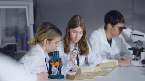 estudiantes en un laboratorio de ciencias usando microscopios