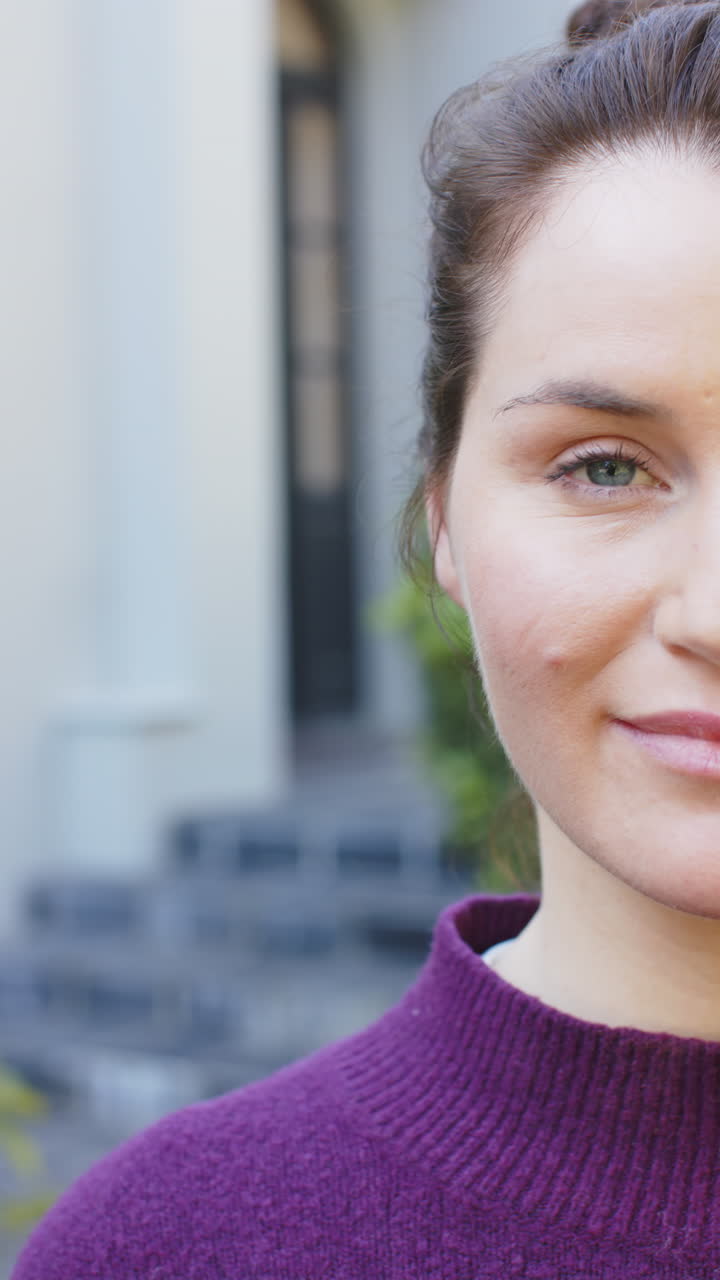 Vertical video of half face of happy caucasian woman standing and smiling in sunny garden