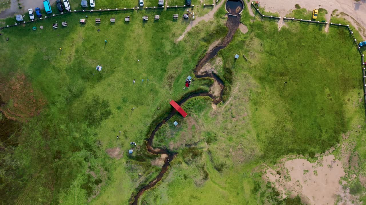 Aerial overhead shot of small river in lush green field