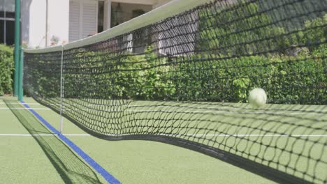 close up of tennis net and ball on tennis court in garden on sunny day