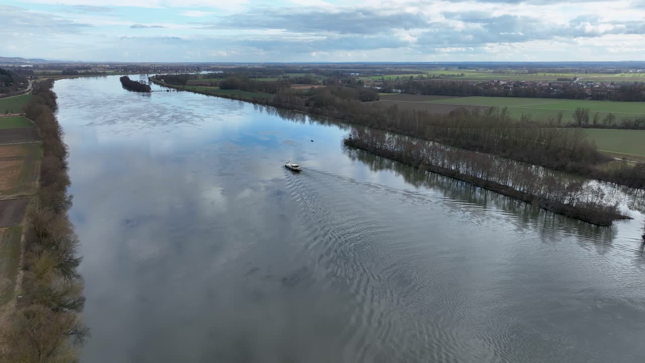 This beautiful footage captures a single boat creating a wake on the glassy surface of a major German river on a calm, overcast day