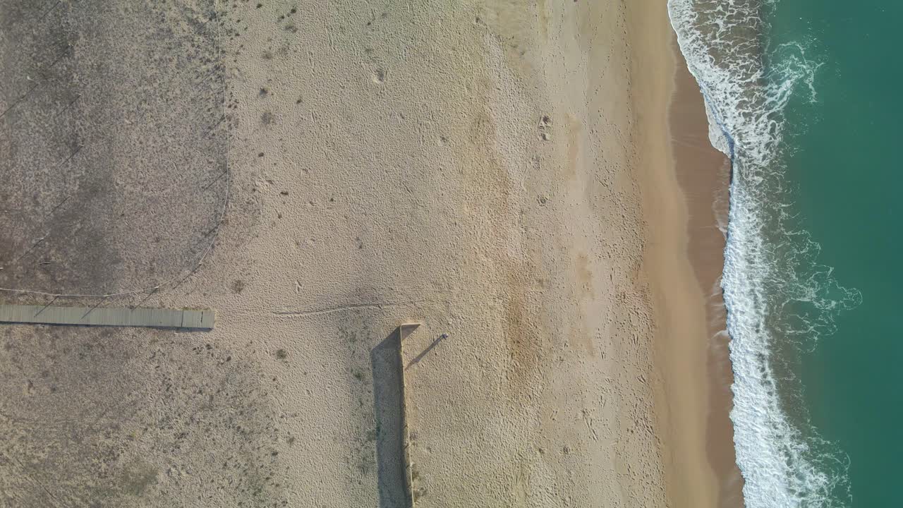 Vista aerea della spiaggia senza persone con drone, acqua turchese, sabbia, passerella di legno
