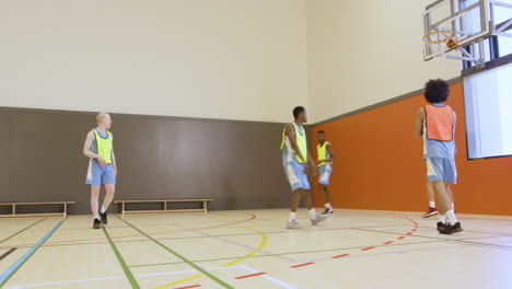 teen basketball players practicing teamwork and shooting hoops in school gym