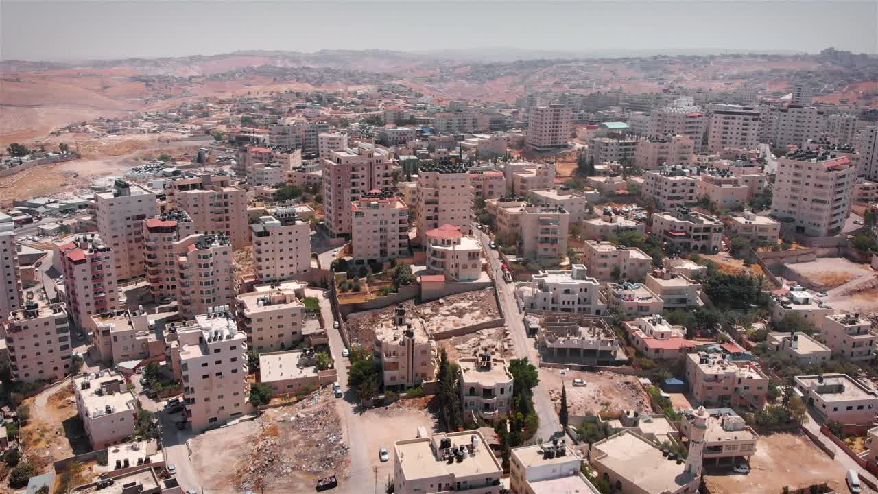Aerial view of a densely populated city or town in a dry, hilly landscape