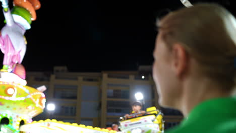woman observing a vibrant amusement park ride at night