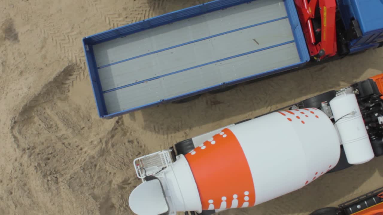 camión mezclador de hormigón y remolque de cama plana en un sitio de construcción