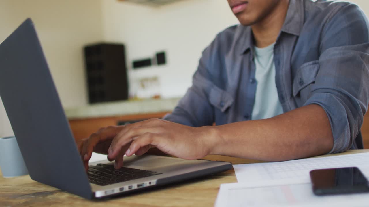 African american man working from home and using laptop