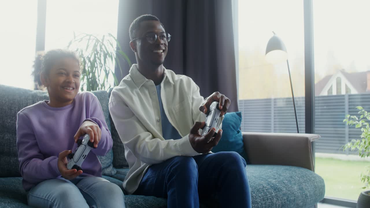 Far og datter spiller videospill sammen hjemme