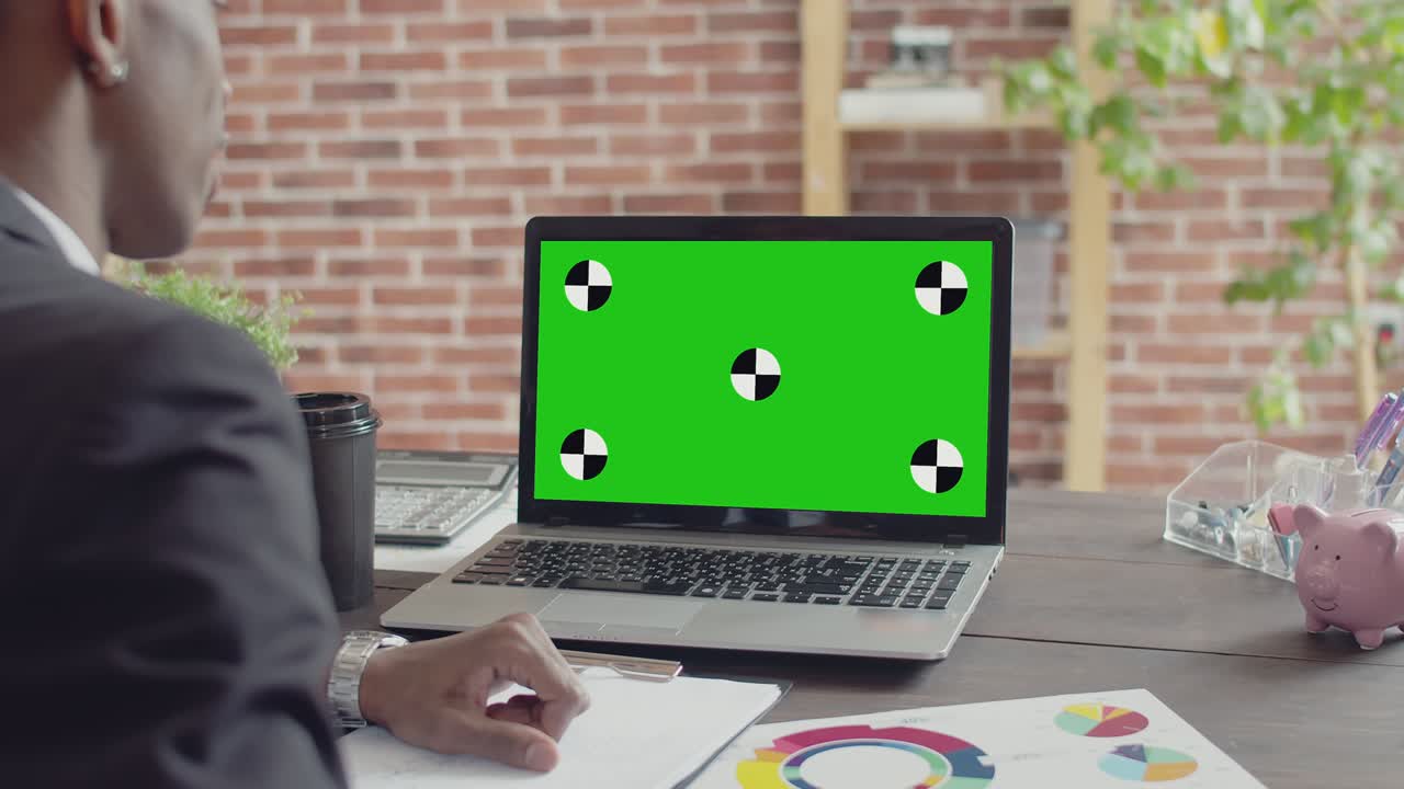 hombre negro trabajador de oficina habla por enlace de video en una pantalla verde portátil en el escritorio. concepto de reuniones en línea y entrevistas