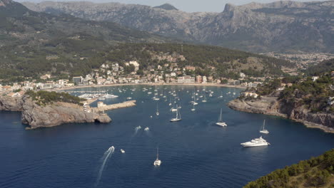 yachts sailing into sea harbor of port de sóller with anchoring boats