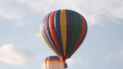 slow tracking shot of colorful hot air balloons moving past puffy clouds