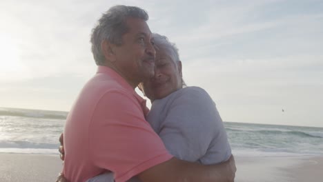 una feliz pareja de graduados hispanos abrazándose en la playa al atardecer