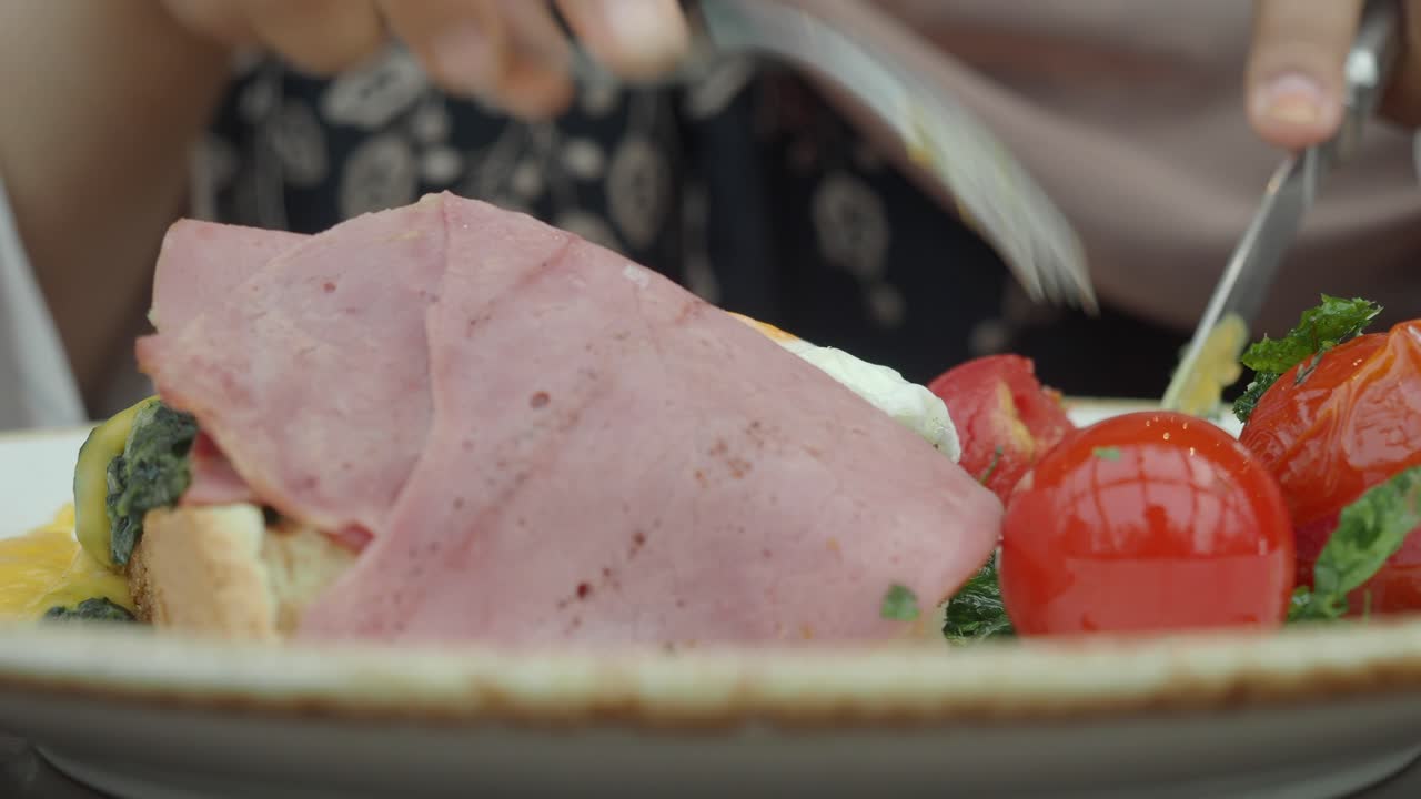 Close-up of food with ham, tomato, and egg on a plate