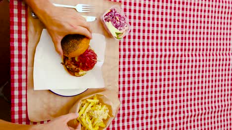 Vertical-video-of-a-man-checking-his-delicious-burger-before-eating-it