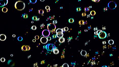 soap bubbles fly and fade in different colors black background soap bubbles fly and flicker with blue green and orange colors black background